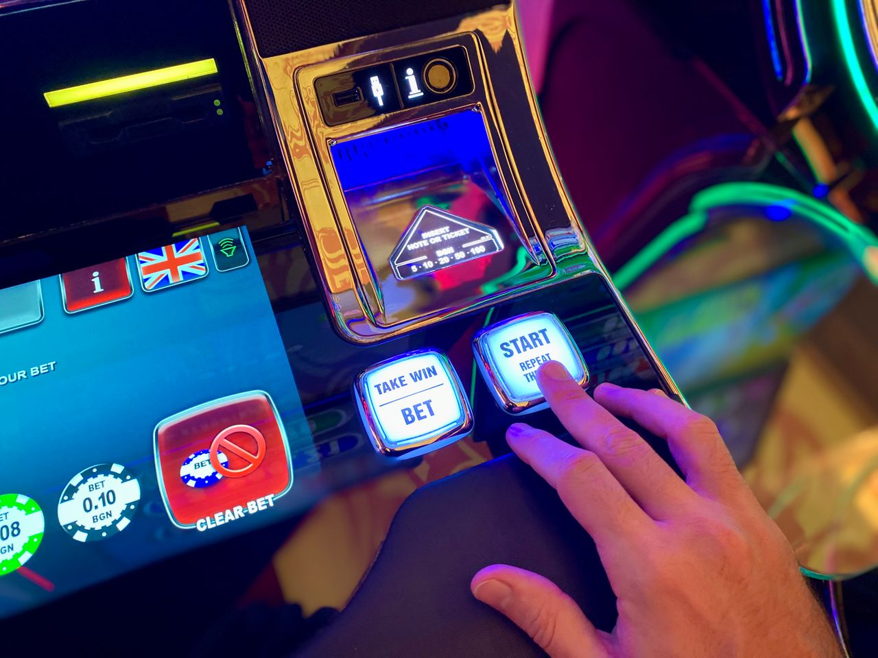 hero-img-02 Hand interacting with buttons on a colorful casino slot machine interface.