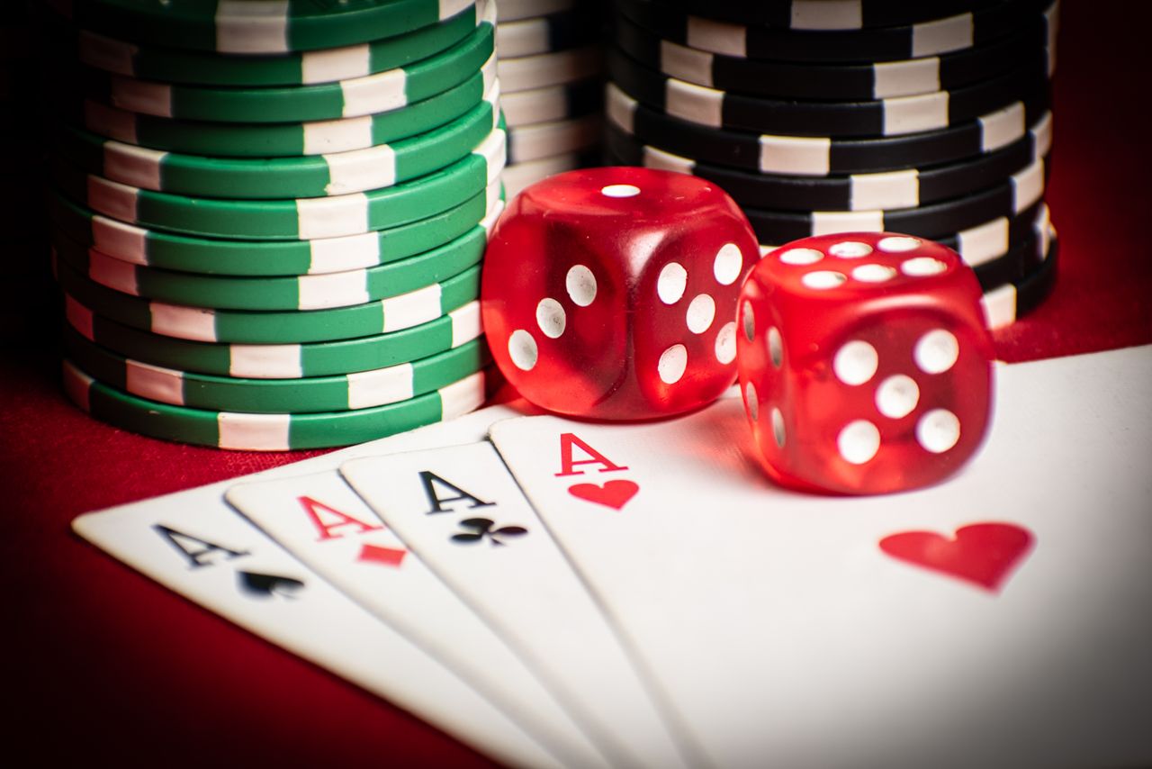 gallery-1 Close-up of poker hand with dice and chips, symbolizing casino gaming.