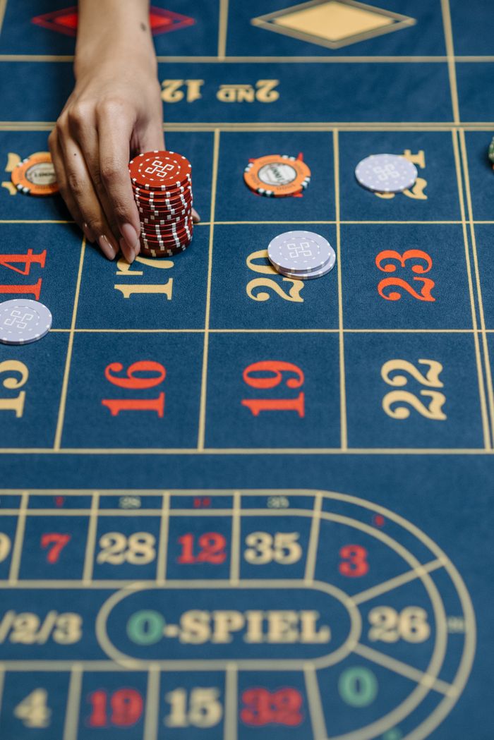 services-03 Close-up of a hand placing chips on a casino roulette table during a game.